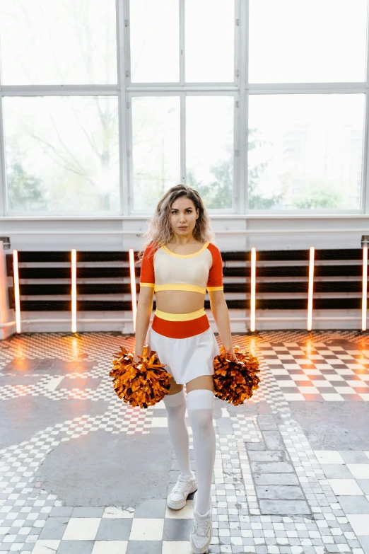 a woman standing on a checkered floor holding a pom poms, an album cover, pexels contest winner, white and orange breastplate, magic uniform university, standing athletic pose, gif