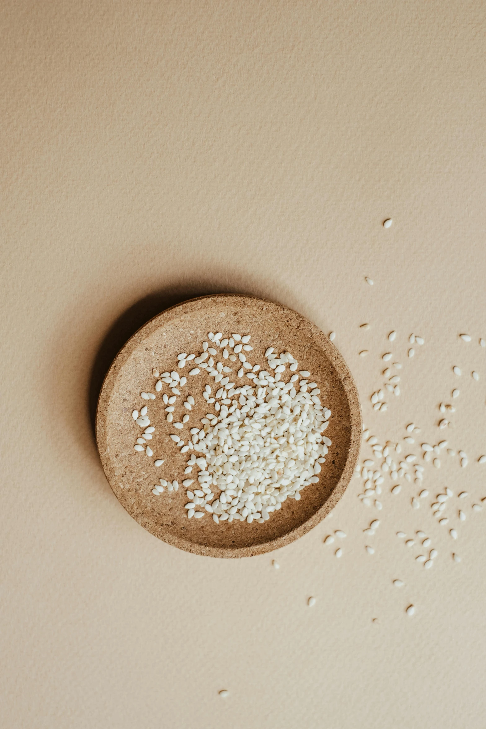 a bowl filled with rice sitting on top of a table, by Alison Geissler, trending on unsplash, mingei, solid background, small finely stippled light, voluptuous sesame seed bun, sustainable materials