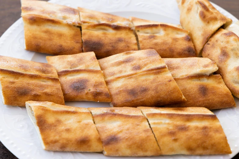 a white plate topped with bread sticks on top of a wooden table, inspired by Géza Dósa, smokey burnt envelopes, fanoos, middle close up shot, panels