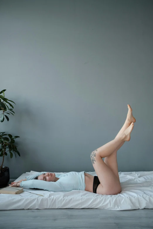 a woman laying on top of a bed next to a potted plant, inspired by Elsa Bleda, arabesque, round thighs, gif, on grey background, full body photograph