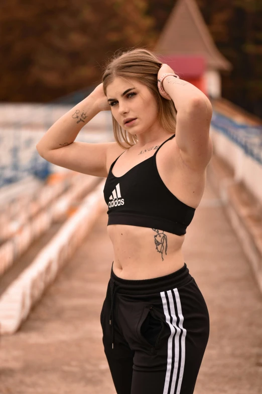 a woman in a sports bra top standing on a bridge, a tattoo, inspired by Elsa Bleda, trending on pexels, wearing adidas clothing, soccer, confident poses, 2263539546]