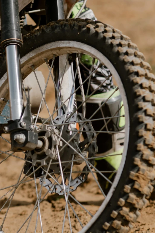 a person riding a dirt bike on a dirt track, detailed alloy wheels, up-close, zoomed in, wheel