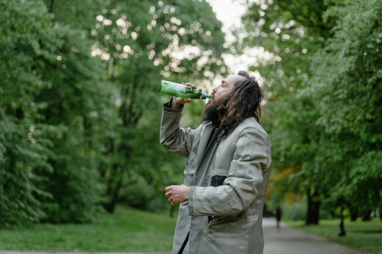 a man with long hair drinking from a bottle, pexels contest winner, green spaces, wearing green jacket, kreuzberg, 🍸🍋