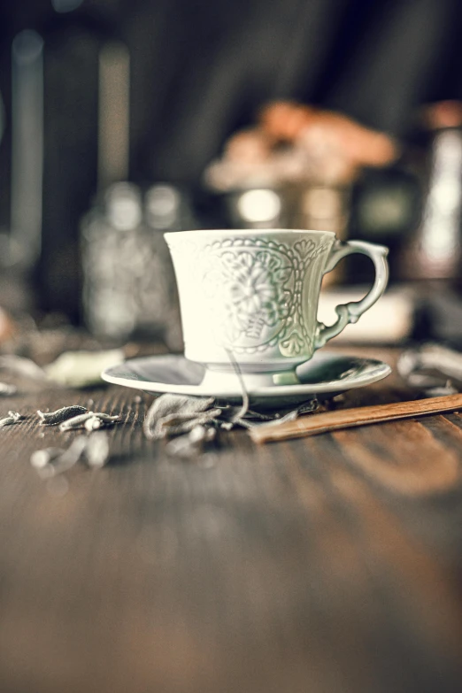 a cup and saucer sitting on top of a wooden table, a still life, unsplash, renaissance, square, absinthe, vintage photo, super intricate