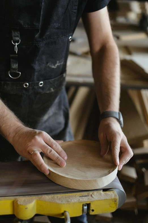 a man is working on a piece of wood, an album cover, inspired by Constantin Hansen, trending on pexels, pancake flat head, leather padding, round-cropped, vessels