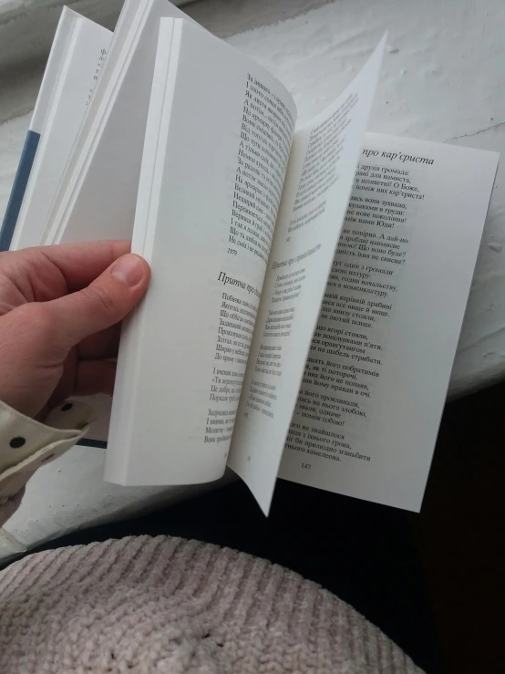 a close up of a person holding a book, low quality photo, poetry, an all white human, interior view