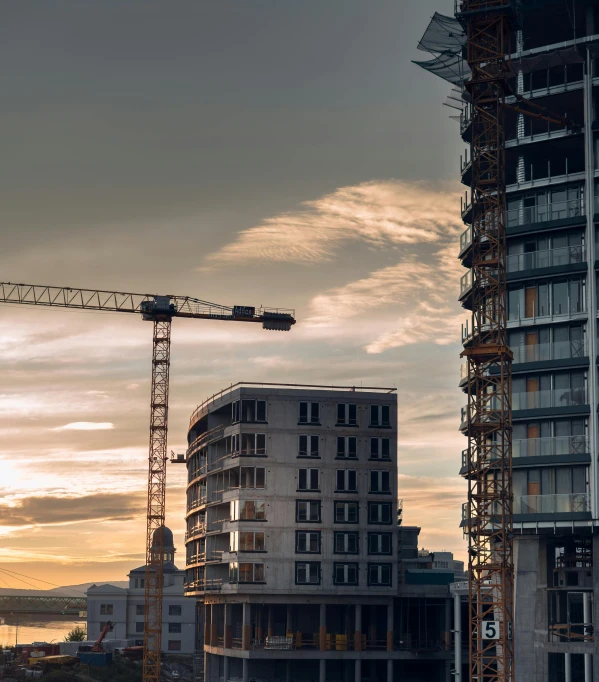 a couple of tall buildings sitting next to each other, by Tobias Stimmer, pexels contest winner, constructivism, under construction, early evening, crane, parallax »