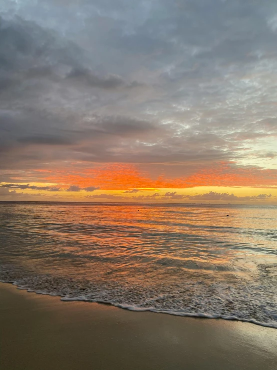 a large body of water sitting on top of a sandy beach, at a beautiful sunset