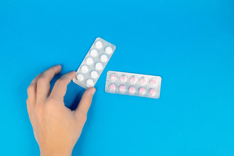 a close up of a person's hand holding a pill pack, inspired by Damien Hirst, pexels, plasticien, stop motion animation, pink white turquoise, two, ( ultra realistic