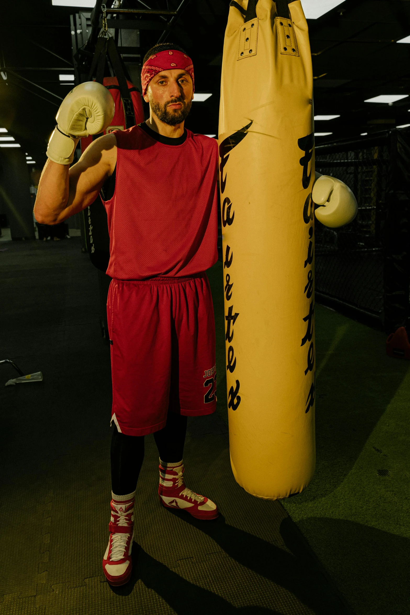 a man standing next to a punching bag, shot with hasselblade camera, full-body-shot, uploaded, maroon