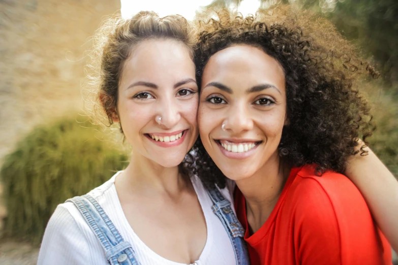 a couple of women standing next to each other, a picture, trending on pexels, mixed race, smiling into the camera, greek ethnicity, multi-part