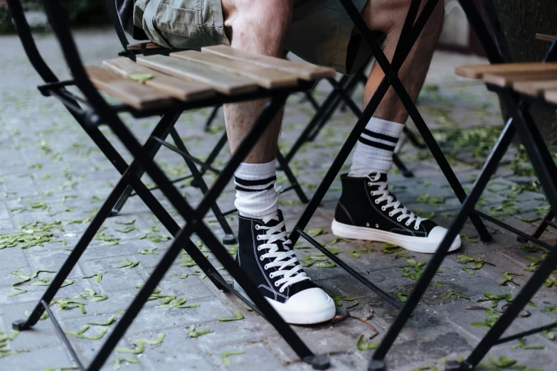 a close up of a person sitting at a table, trending on pexels, battle shoes, in the garden, tall man, white and black