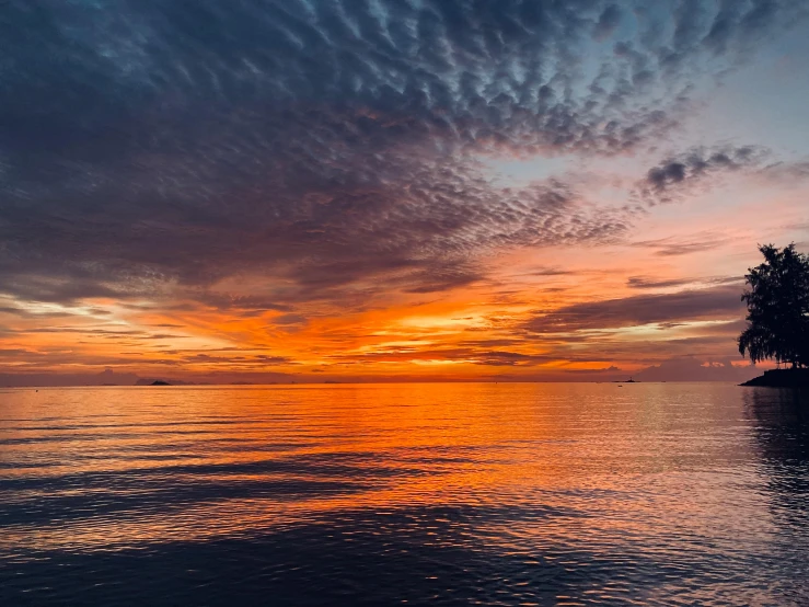 a large body of water with a sunset in the background, by Carey Morris, pexels contest winner, fan favorite, red clouds, calm seas, sunset panorama