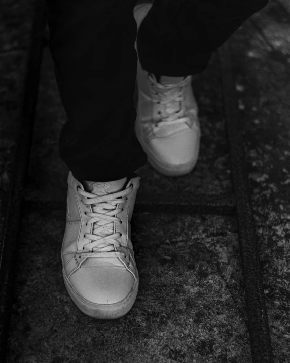 a black and white photo of a person's shoes, wearing white clothes, white metallic, cinematic front shot, lowres
