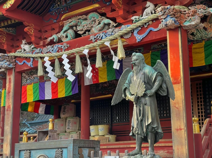 a statue of an angel in front of a building, a statue, inspired by Sesshū Tōyō, pexels contest winner, sōsaku hanga, colourful biomorphic temple, in an ancient altar, old man, spirits covered in drapery