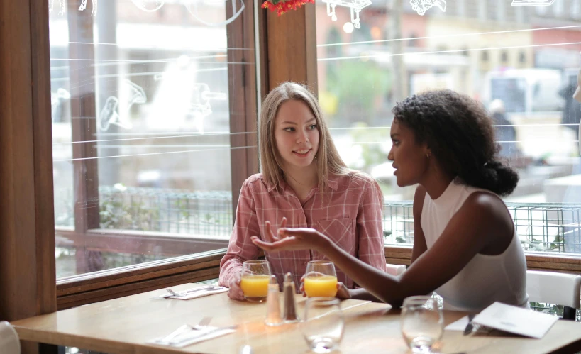 two women sitting at a table in a restaurant, pexels, renaissance, npc talking, reaching out to each other, morning time, unedited