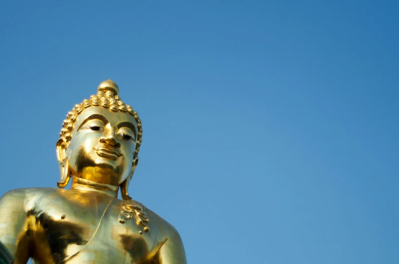 a golden buddha statue with a blue sky in the background, a statue, unsplash, shot on sony a 7, smooth golden skin, thumbnail, screensaver