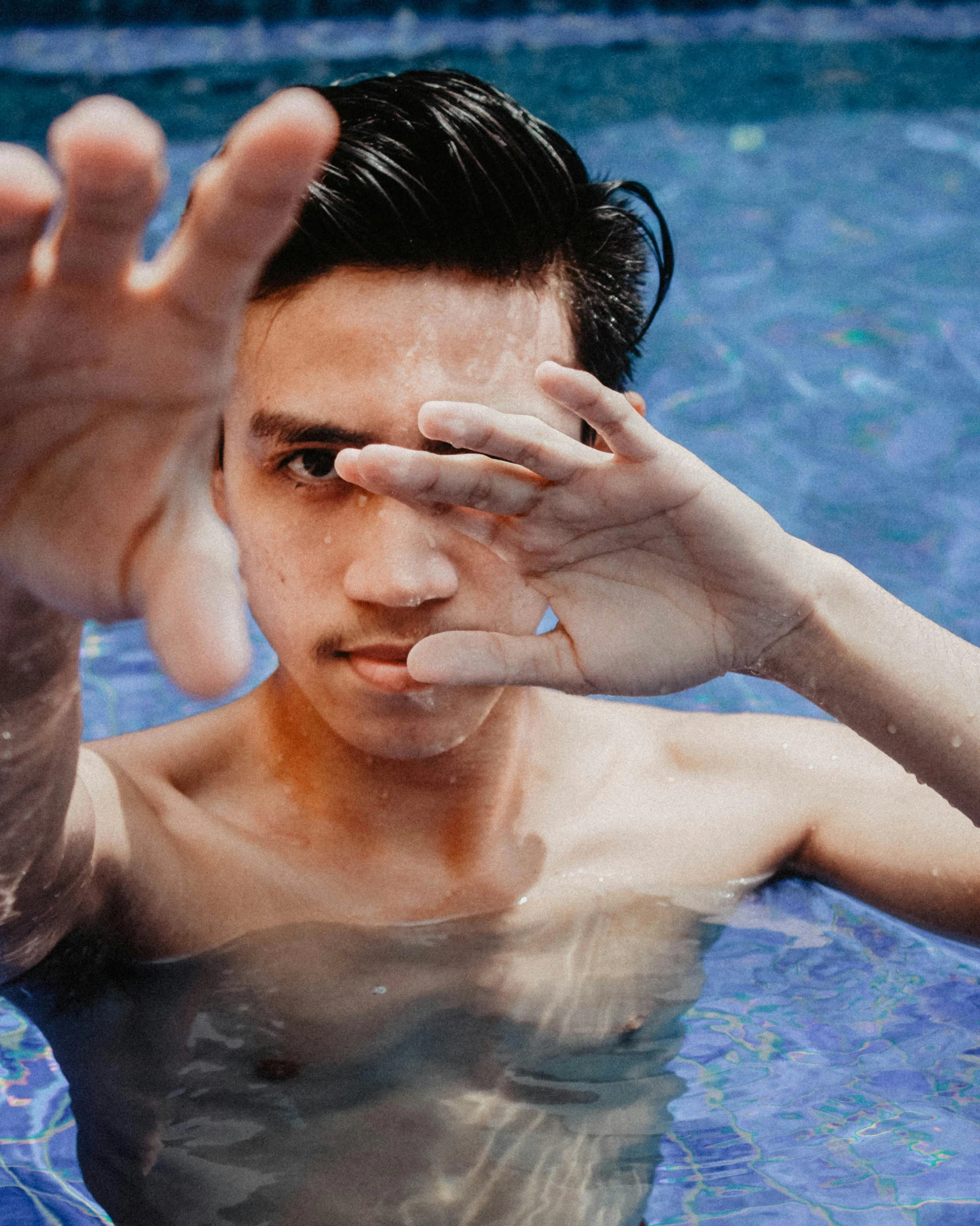 a man in a pool making a stop sign with his hands, inspired by Ren Hang, unsplash, sumatraism, lgbt, lovingly looking at camera, asian face, 2019 trending photo