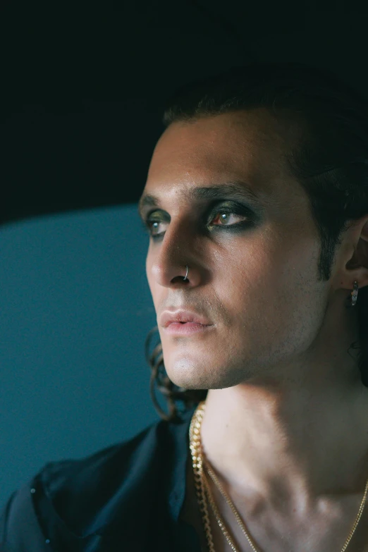 a close up of a person wearing a necklace, an album cover, inspired by Eugene Leroy, trending on pexels, handsome male vampire, gazing dark brown eyes, car shot, cait miers