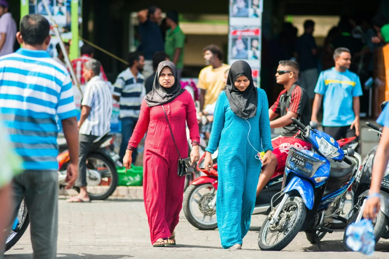 a group of people walking down a street, hurufiyya, male and female, motorbike, square, full frame image