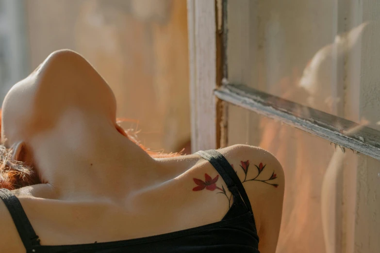 a woman laying on top of a window sill, a tattoo, inspired by Elsa Bleda, trending on pexels, temporary tattoo, leafs, smooth red skin, over his shoulder