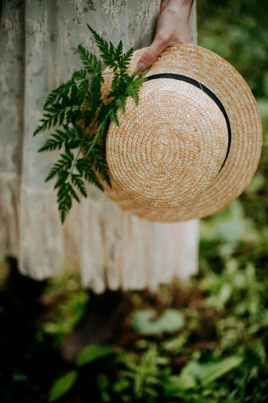 a woman in a white dress holding a straw hat, inspired by Kate Greenaway, unsplash, wreath of ferns, detail shot, hanging, wearing a french beret