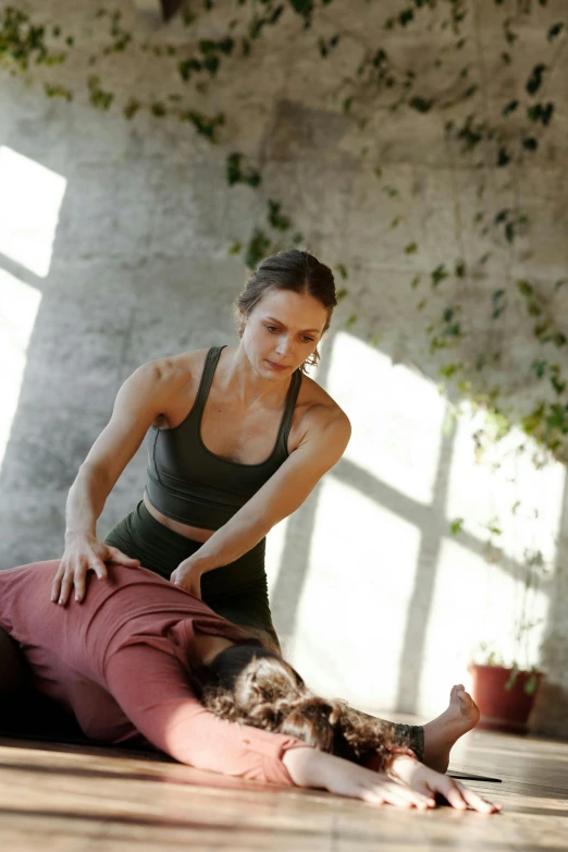 a woman doing a yoga pose on the floor, by Jessie Algie, pexels contest winner, renaissance, woman holding another woman, arched back, lush botany, looking across the shoulder