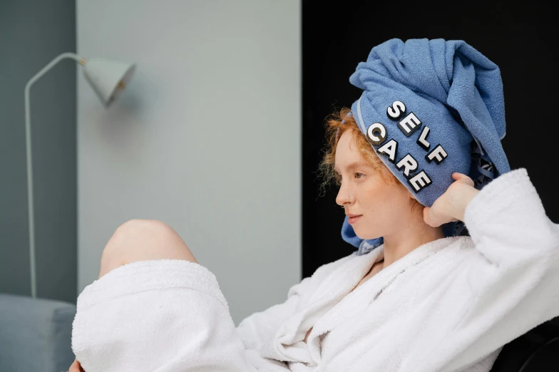 a woman sitting in a chair with a towel on her head, trending on pexels, a redheaded young woman, wearing a blue robe, headspace, idealised