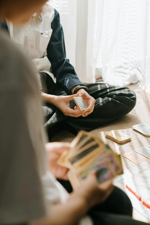 a couple of people sitting on the floor playing a game, by Julia Pishtar, pexels contest winner, tarot card frame, grainy, the woman holds more toys, zoomed in shots