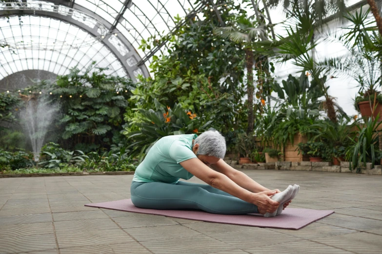 a woman sitting on a yoga mat in a greenhouse, pexels contest winner, elderly woman, plain stretching into distance, sydney park, back arched
