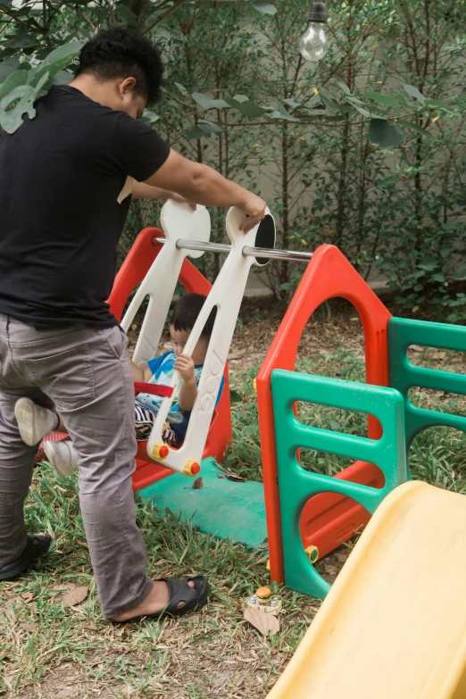 a man standing next to a child on a slide, by Federico Zuccari, process art, hiding behind obstacles, in the garden, multi-part, toys