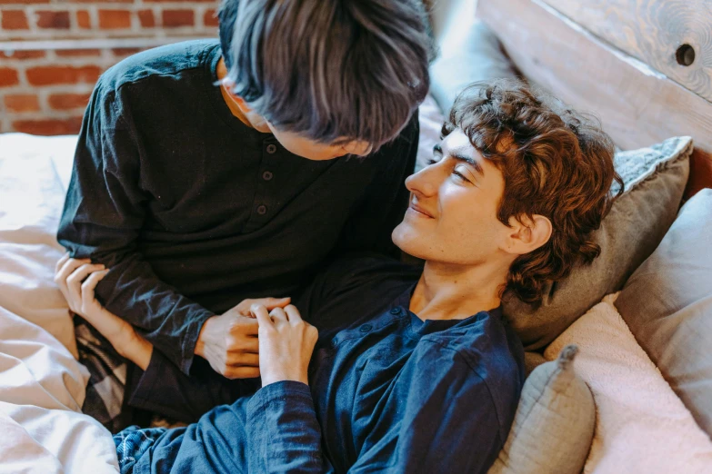a couple of young men laying on top of a bed, by Carey Morris, trending on pexels, renaissance, arm around her neck, adam ondra, sitting on the couch, supportive