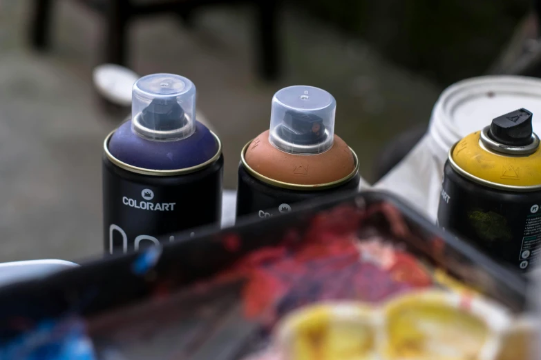 a group of cans of paint sitting on top of a table, notan art, rich cold moody colours, matt colors outdoor, sprays
