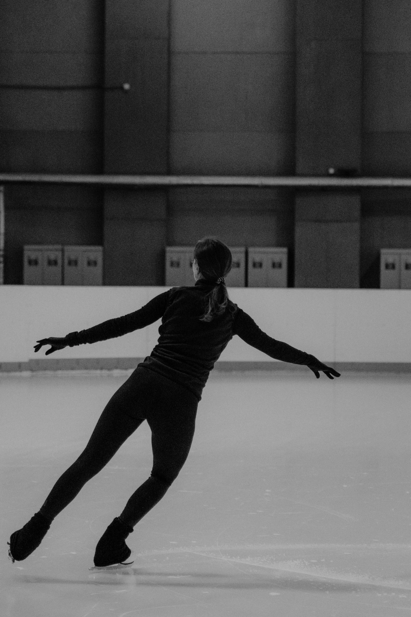 a man riding a skateboard on top of an ice rink, a black and white photo, arabesque, she is floating in the air, uploaded, indoor, no - text no - logo