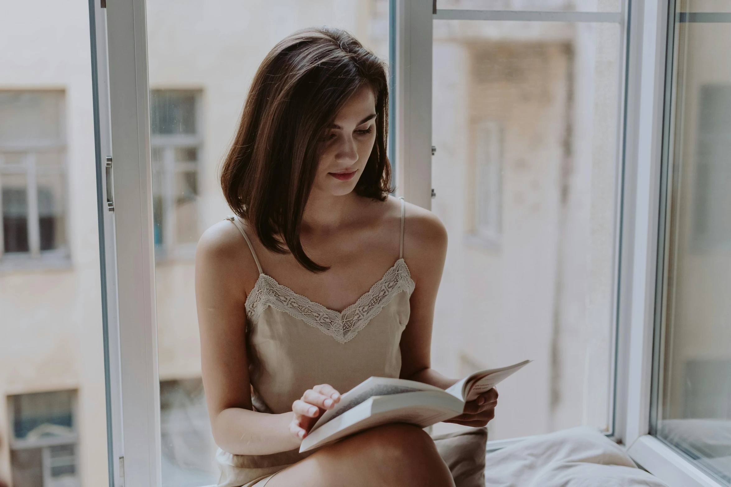 a woman sitting on a bed reading a book, by Emma Andijewska, pexels contest winner, happening, wearing a camisole, avatar image, handsome girl, candid