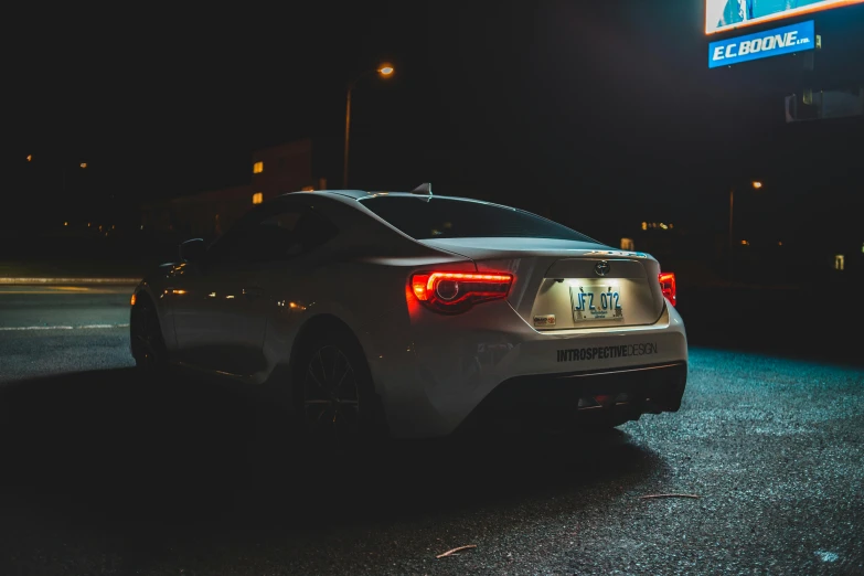 a car parked in a parking lot at night, pexels contest winner, hurufiyya, ae 8 6, back turned, white metallic, instagram picture