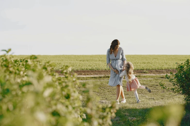 a woman standing next to a little girl in a field, walking away from the camera, wine, press shot, canvas