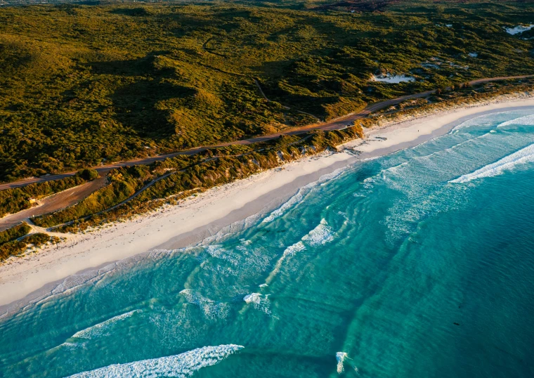 a large body of water next to a sandy beach, by Lee Loughridge, pexels contest winner, happening, aerial footage, whealan, road trip, taken at golden hour