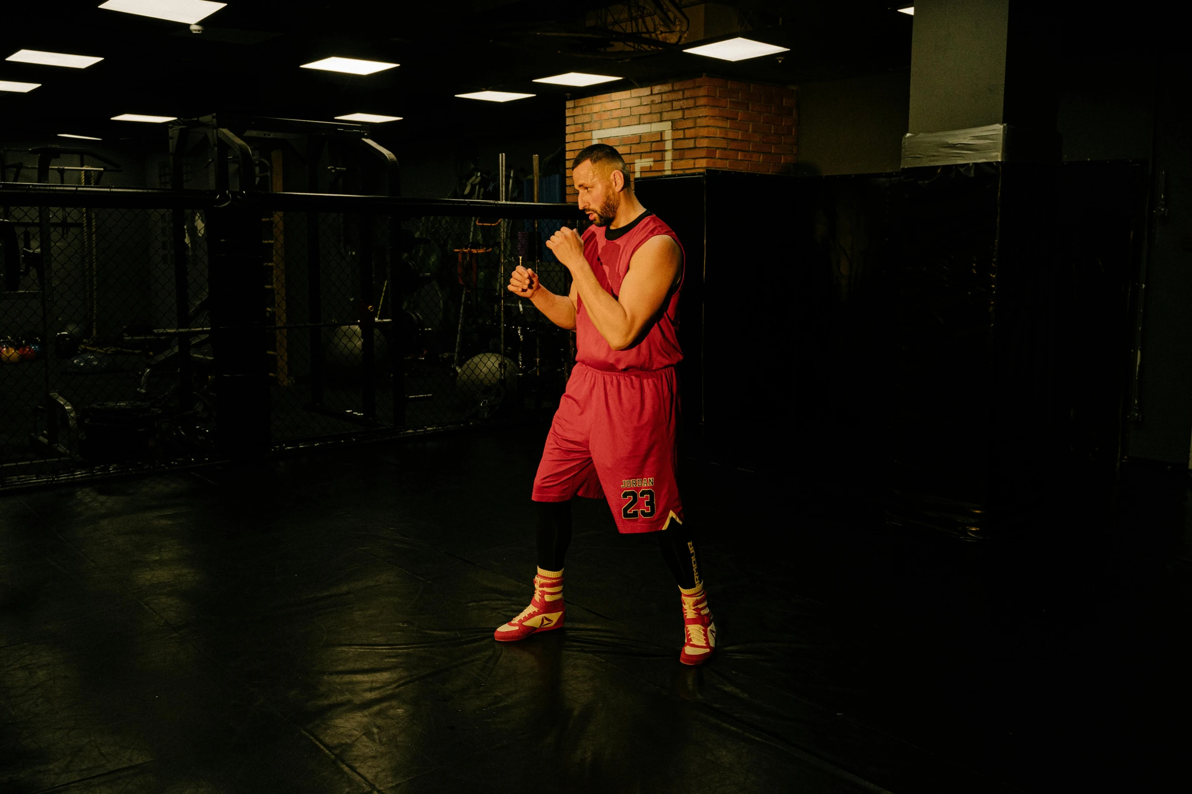 a man standing in a gym holding a ball, a hologram, inspired by Ma Quan, figuration libre, boxing stance, shot with hasselblade camera, train with maroon, conor mcgregor