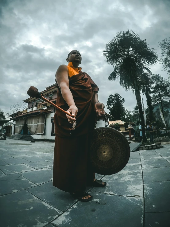 a monk holding a gong in front of a building, pexels contest winner, full body profile camera shot, ( ( theatrical ) ), dressed in shako, indian