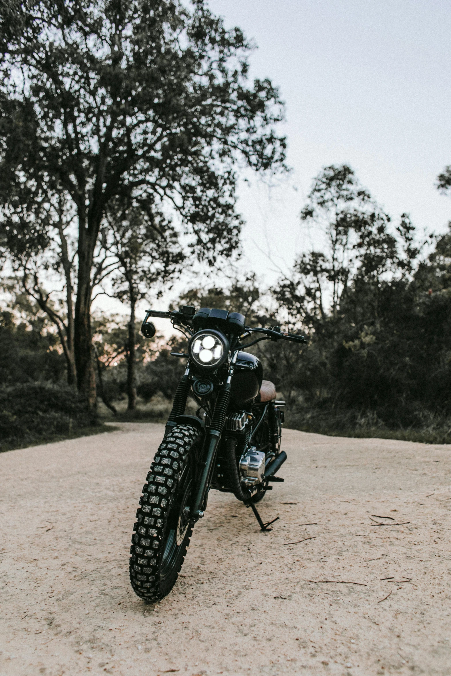 a motorcycle parked on the side of a dirt road, a portrait, unsplash contest winner, round headlights, sydney park, triumph, profile image