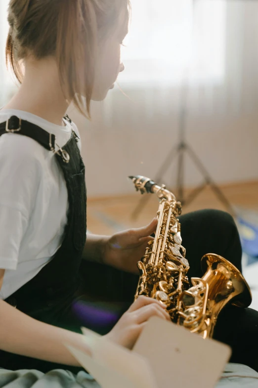 a girl sitting on a bed playing a saxophone, trending on pexels, neck zoomed in, 15081959 21121991 01012000 4k, feat of artistic achievement, schools