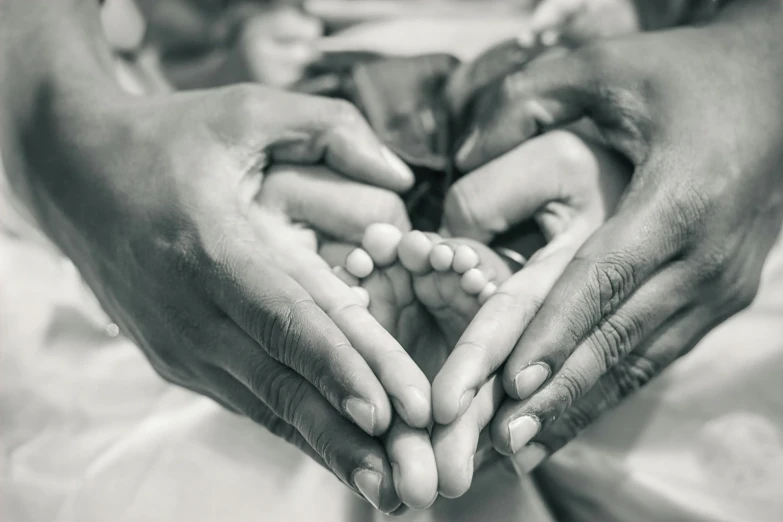 two people making a heart with their hands, a black and white photo, pexels contest winner, process art, human babies, varying ethnicities, tiny feet, healthcare