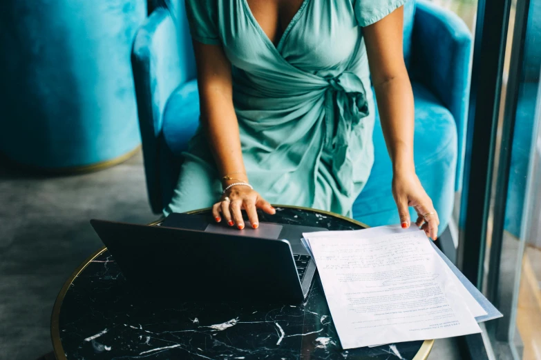 a woman sitting at a table with a laptop, by Julia Pishtar, trending on unsplash, figuration libre, teal suit, wearing a cocktail dress, 15081959 21121991 01012000 4k, high angle shot