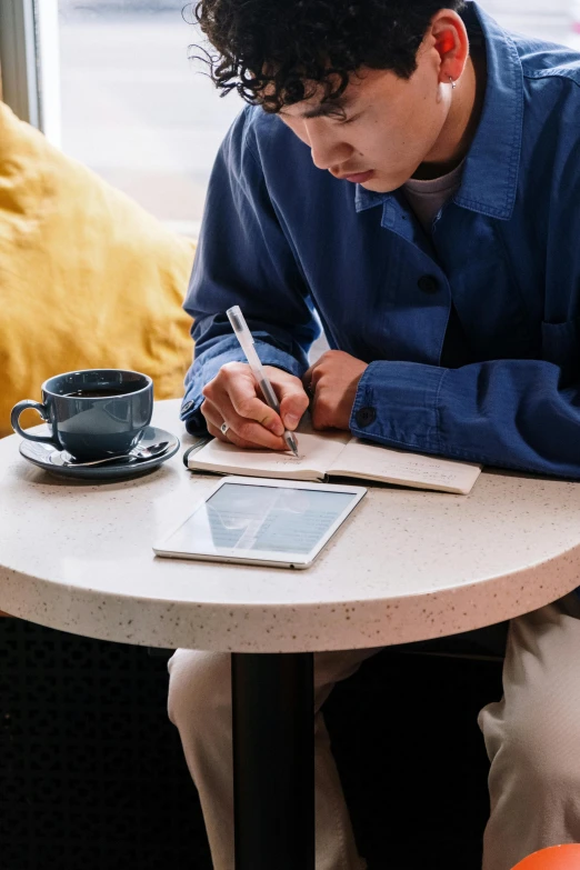 a man sitting at a table writing on a tablet, by Nicolette Macnamara, morning coffee, david luong, designer product, multiple stories