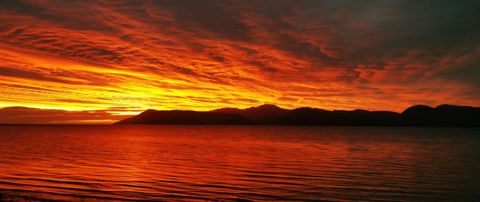 a sunset over a body of water with mountains in the background, on background red lake on fire, nature photo