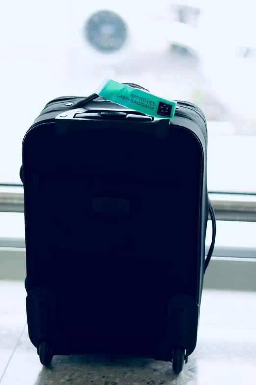 a piece of luggage sitting in front of a window, black and teal paper, medium sensor, tag, seafoam green