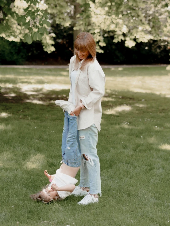 a couple of women standing on top of a lush green field, by Nina Hamnett, happening, toddler, jeans, in a park, low quality photo