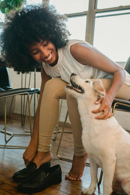 a woman petting a white dog on the floor, pexels contest winner, renaissance, african american young woman, smiling playfully, sitting on top a table, zoomed in