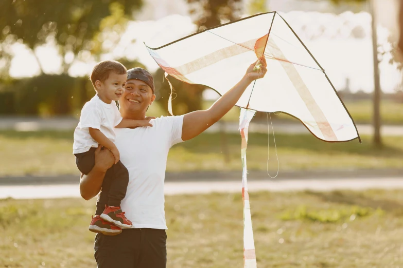 a woman holding a child while flying a kite, pexels contest winner, handsome man, square, sydney park, islamic